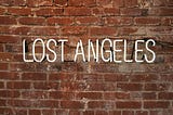 A picture of lit up words “lost Angeles” against a brick wall; a play of words to depict being lost