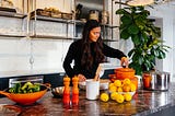 A woman in a kitchen with colourful equipment and a bowl of lemons