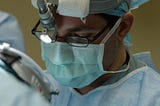 surgeon’s face wearing mask looking down onto patient