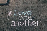 Love One Another written on sidewalk.