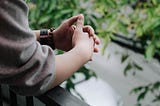 Photo of a person‘s clasped hands, as if deep in the process of making a decision.