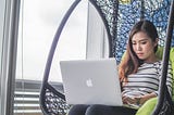woman sitting in a comfortable chair working on macbook laptop