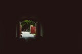 Black room with a doorway open, light shining in and a path