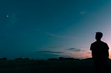 A man sitting and thinking in nature while it is sunset