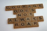 scrabble tiles spelling out the phrase ‘courage does not always roar’