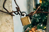 Brass padlock on brown metal fence