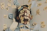 Man with sticky notes overloaded over his face & the desk.