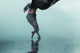 Grey misty back ground. A man being blown by the wind on a beach.