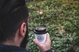 A man carrying one to-go cup of coffee