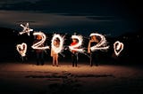 Um grupo de pessoas manuseando sparklers enquanto fazem um desenho de “2022” com algumas estrelas e corações. Fonte: Kenta Kikuchi