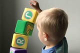 Small child stacking blocks with letters on them