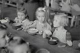 Young children eating breakfast in the cafeteria. Photo from the 30s?
