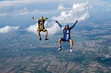 Two men facing camera with arms and legs spread open while skydiving