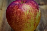 A red apple, possibly a Gala, possibly organic, on a table