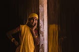 An Indian woman leans against a concrete pillar