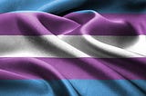 An image depicting a portion of a transgender pride flag. It is slightly wrinkled to play with light and shadow.