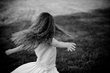 Girl twirling in a field. It’s in black-and-white, so you can tell it’s art