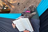 Author reading in a hammock with a shih tzu laying on her lap