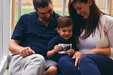 Young boy sits between his parents holding a baby ultrasound image.