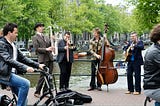 group of musicians playing music with water nearby