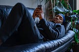 A Man Lying on a Sofa Holding a Cell Phone