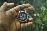 Close-up of a hand holding a wristwatch, symbolizing time passing and waiting for the right moment.