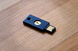 A YubiKey laying on a wodden surface.