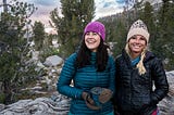 A brunette and blonde women hiking in the mountains.
