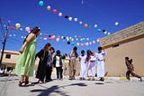 Children gather outside at a child-friendly space under balloons.