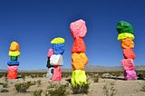 brightly painted rocks stacked up, like pillars, in a desert
