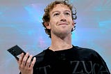 Mark Zuckerberg smiles as he looks up from his phone.