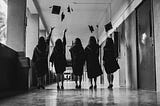 A group of graduates throw their academic mortarboards in the air