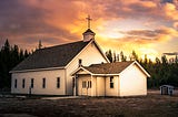 Rural church with a sunset behind it
