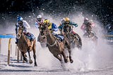 Horses racing on a track lightly covered in snow
