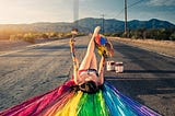 woman painting a rainbow on a country street