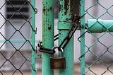 A green gate with a padlock.