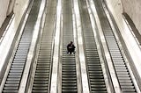 A young man sits on an empty escalator