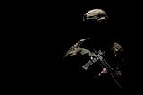 A soldier holding a machine gun is obscured in the darkness.