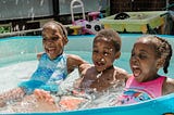 three black children playing in a pool