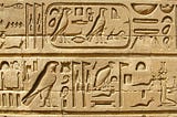 An area of a stone carving of ancient Egyptian hieroglyphs chiselled with great care and precision. The symbols shown are presented in two rows separated by a line. Some symbols are within a rounded-off box as if for emphasis.