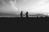 Silhouette of a couple holding hands at dusk.