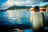 Man in blue shorts sitting by the lake and mountains