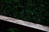 Many raindrops falling on a ledge creating ripples