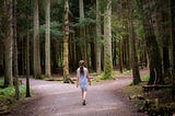 A young girl at a crossroads in a forest.