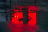 Red light reflected on a damp road surface