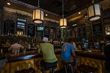 Two man sitting at a bar facing away from each other. Photo by mana5280 on Unsplash