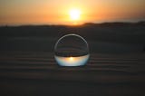 Image of the sunset with a glass ball set in the sun, the glass ball in focus, the sunset not.