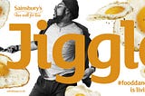 Picture of a bearded dude dancing while apparently flipping a larger than even pancake-sized fried egg out of a frying pan. These eggs fly about him with the word “Jiggle” in very large text written over him. #FoodDancing is living well, it says.