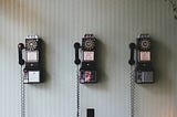 Three dial and handpiece telephones on a wall