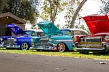 Three antique cars with their hoods up